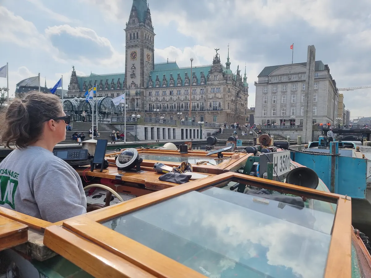 Schiffsführer am Steuerstand einer Barkasse vor dem Hamburger Rathaus